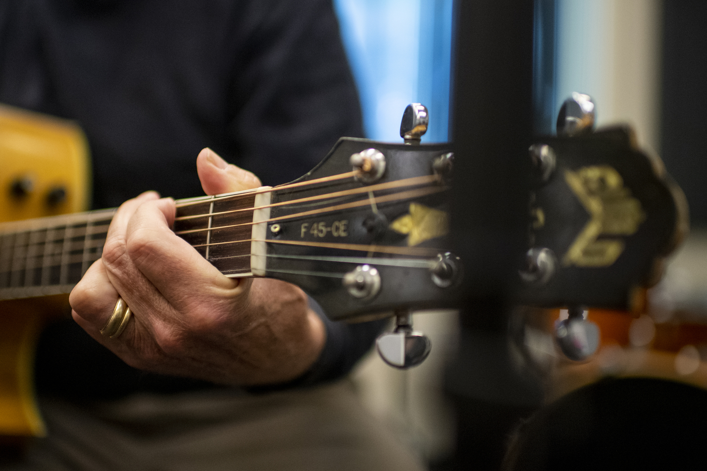 A hand is holding a guitar while playing music.