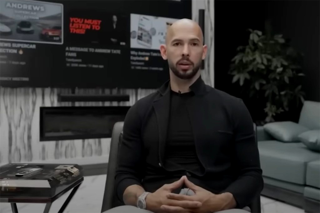 Andrew Tate posed looking at the camera in front of a computer screen