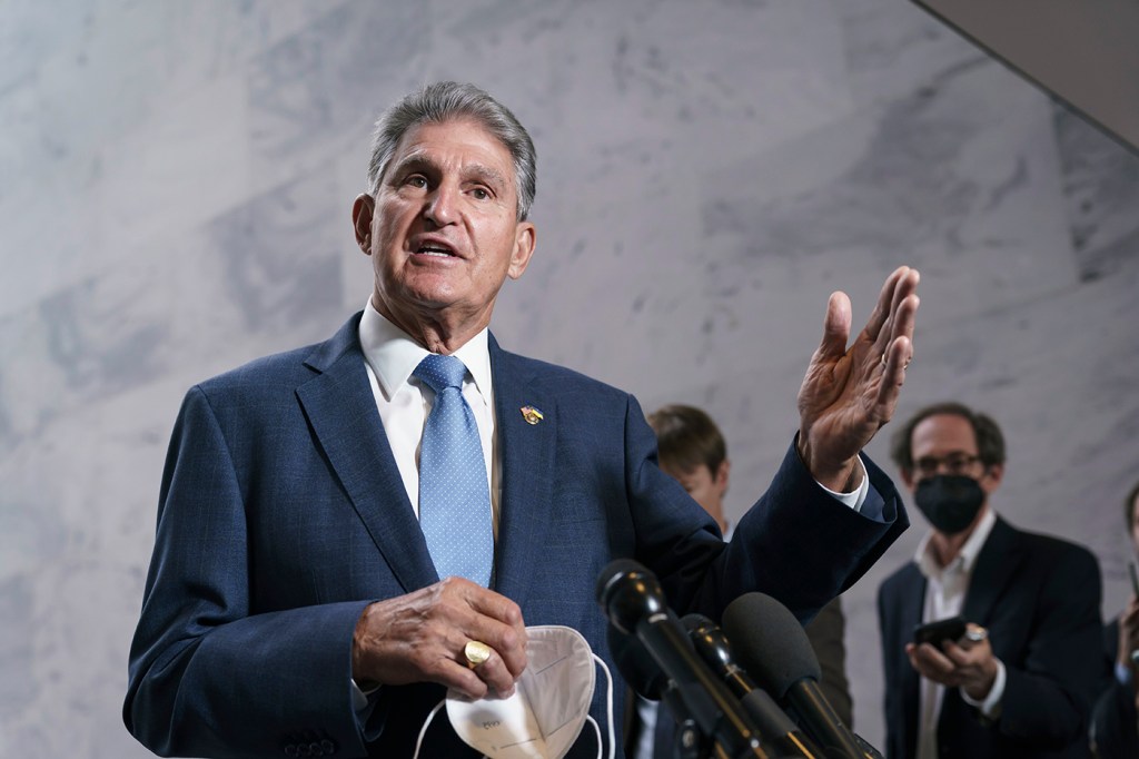 man wearing blue suit and tie gestures with left hand