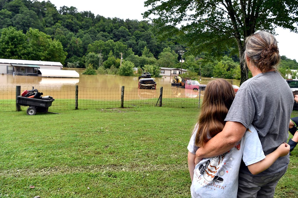 woman with her arm around a child staring at her property