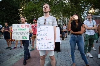 man holding protest sign with more protesters in the background