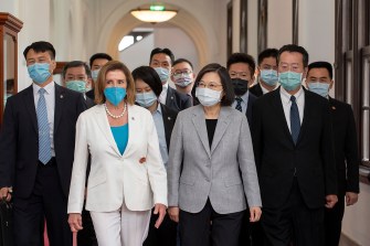 two masked women walking with a crowd of masked men and women behind them