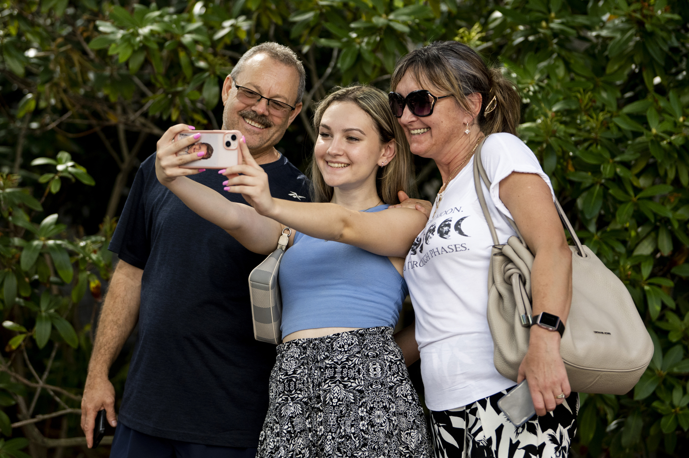 Two parents are smiling together while taking a picture with their child. 