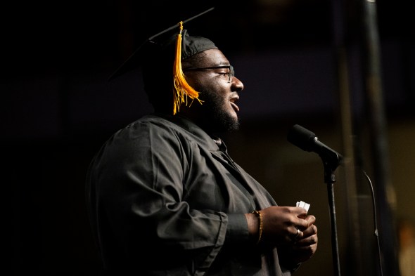 A person wearing a graduation cap and gown is talking into a microphone at Northeastern's 2022 Convocation.