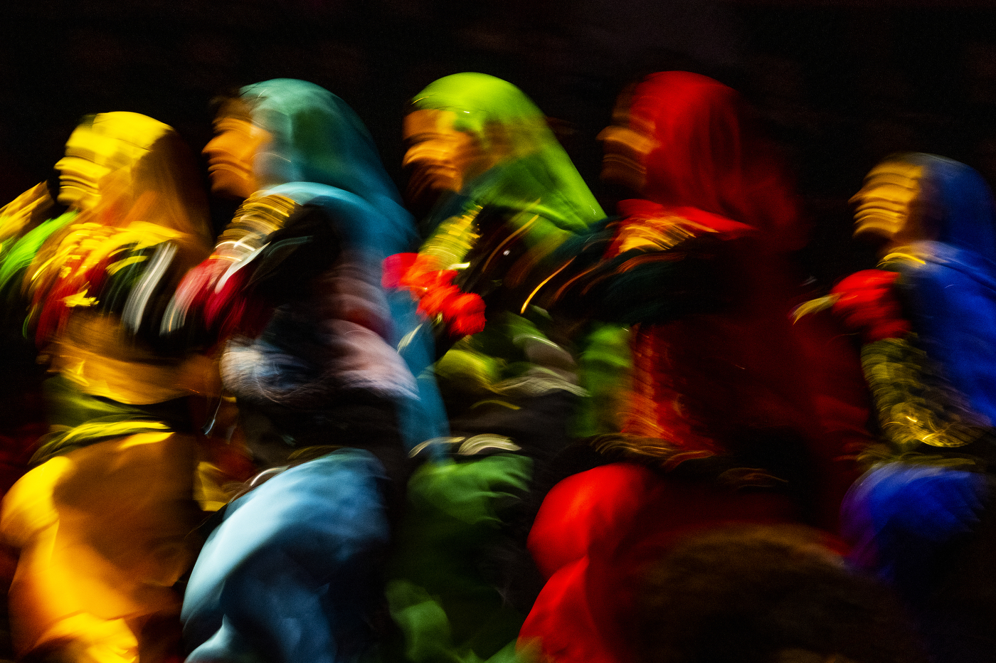 Five people wearing bright-colored outfits are dancing together at Northeastern's 2022 Convocation.