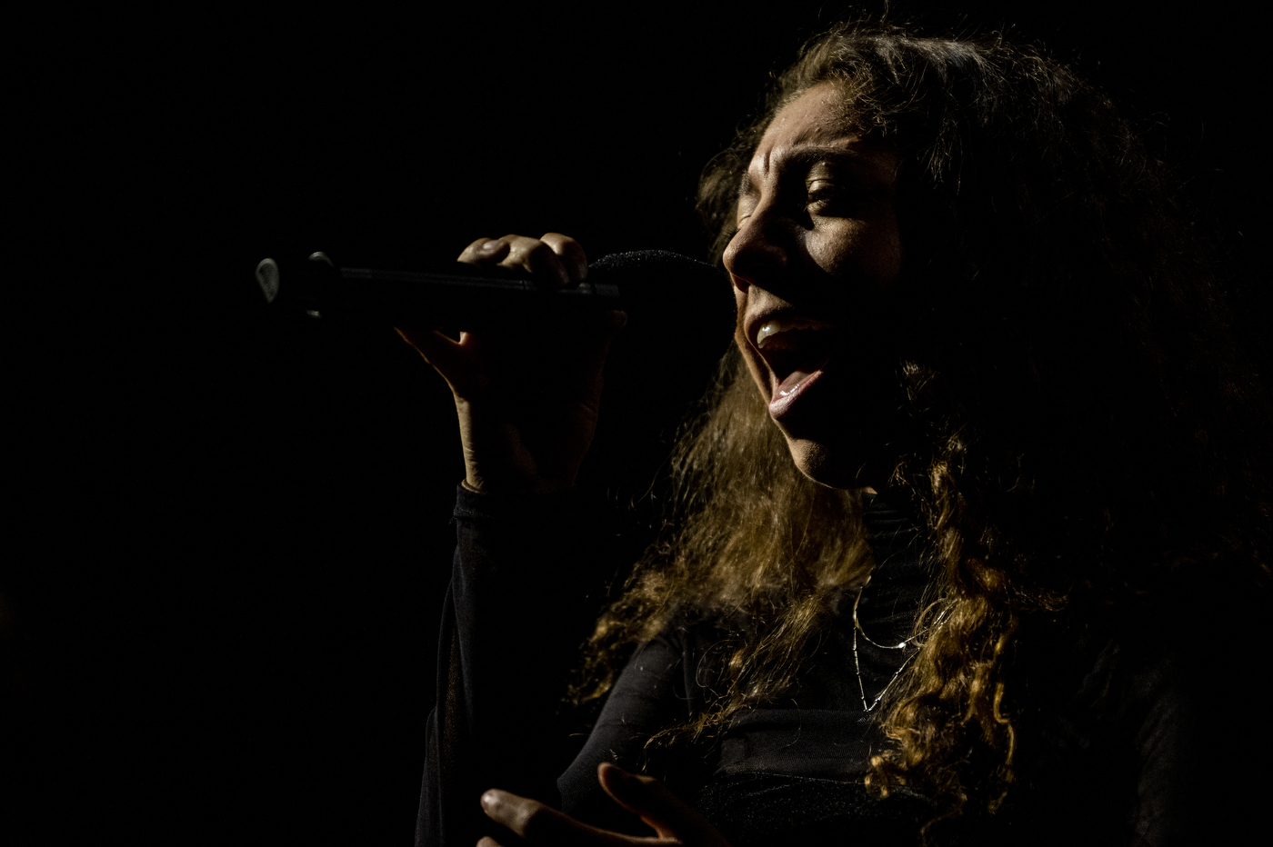 A dimly lit is holding a microphone while singing at Northeastern's 2022 Convocation. 