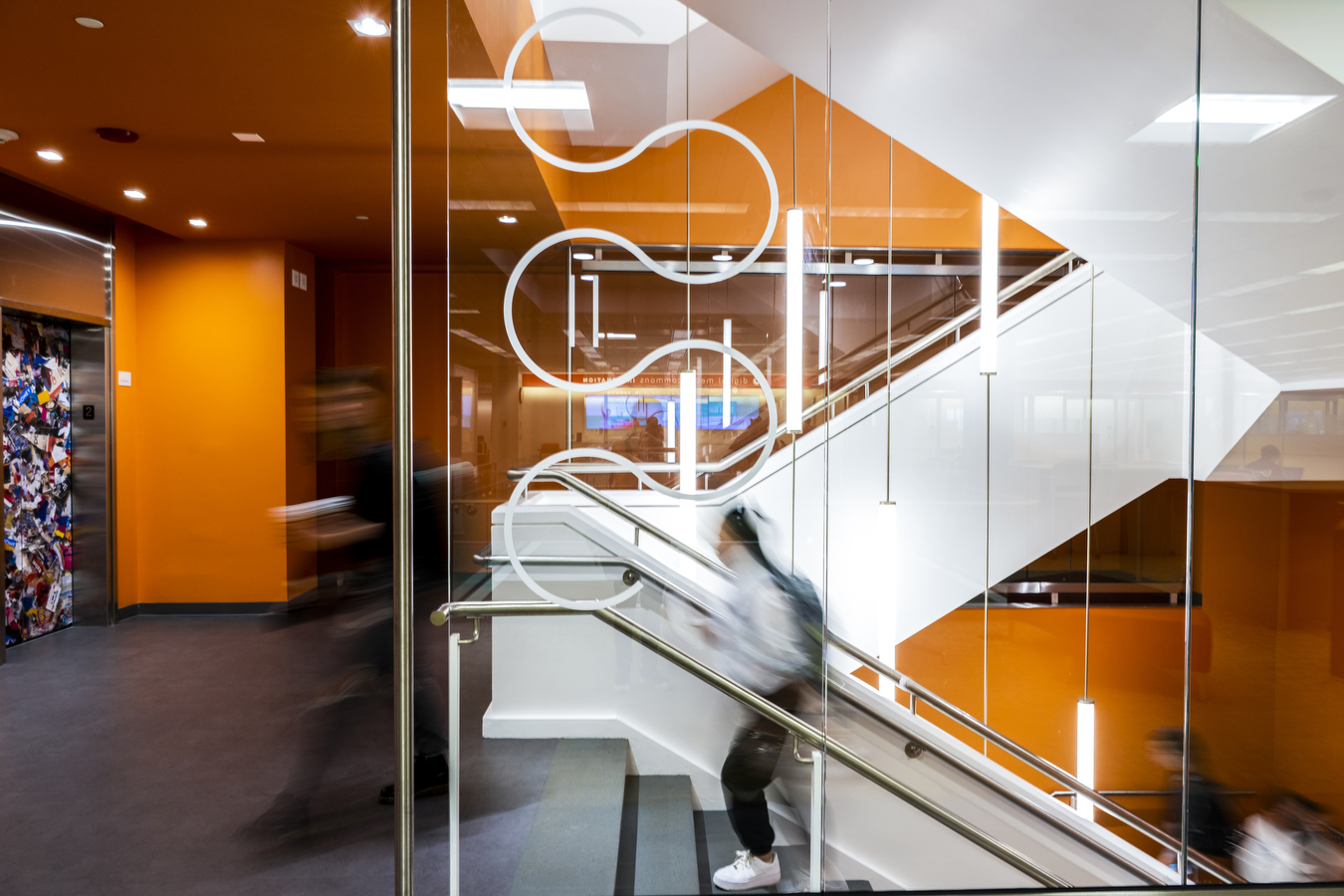 Folks walking through the Snell library, past an orange wall