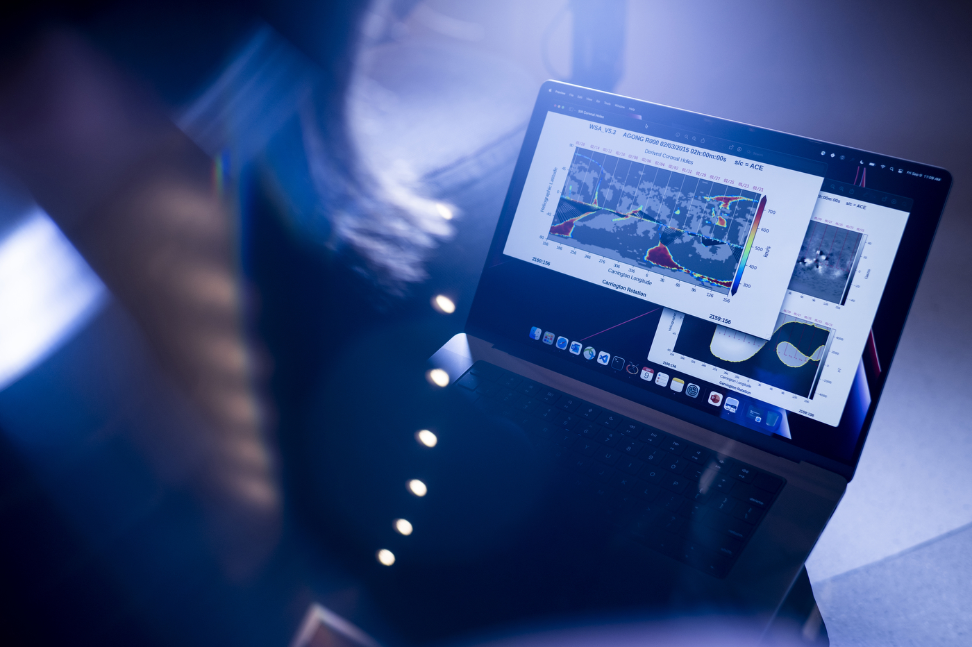 A person working at NASA is holding a laptop that displays a large graph on its screen. 