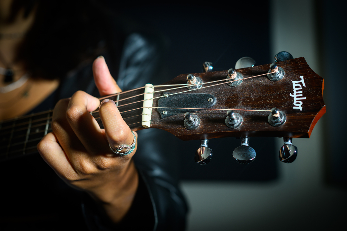 A person is holding an acoustic guitar while playing the instrument.