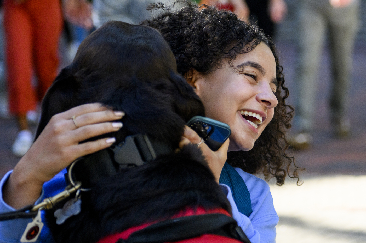 A person wearing a grey shirt is petting a black service dog at Northeastern.