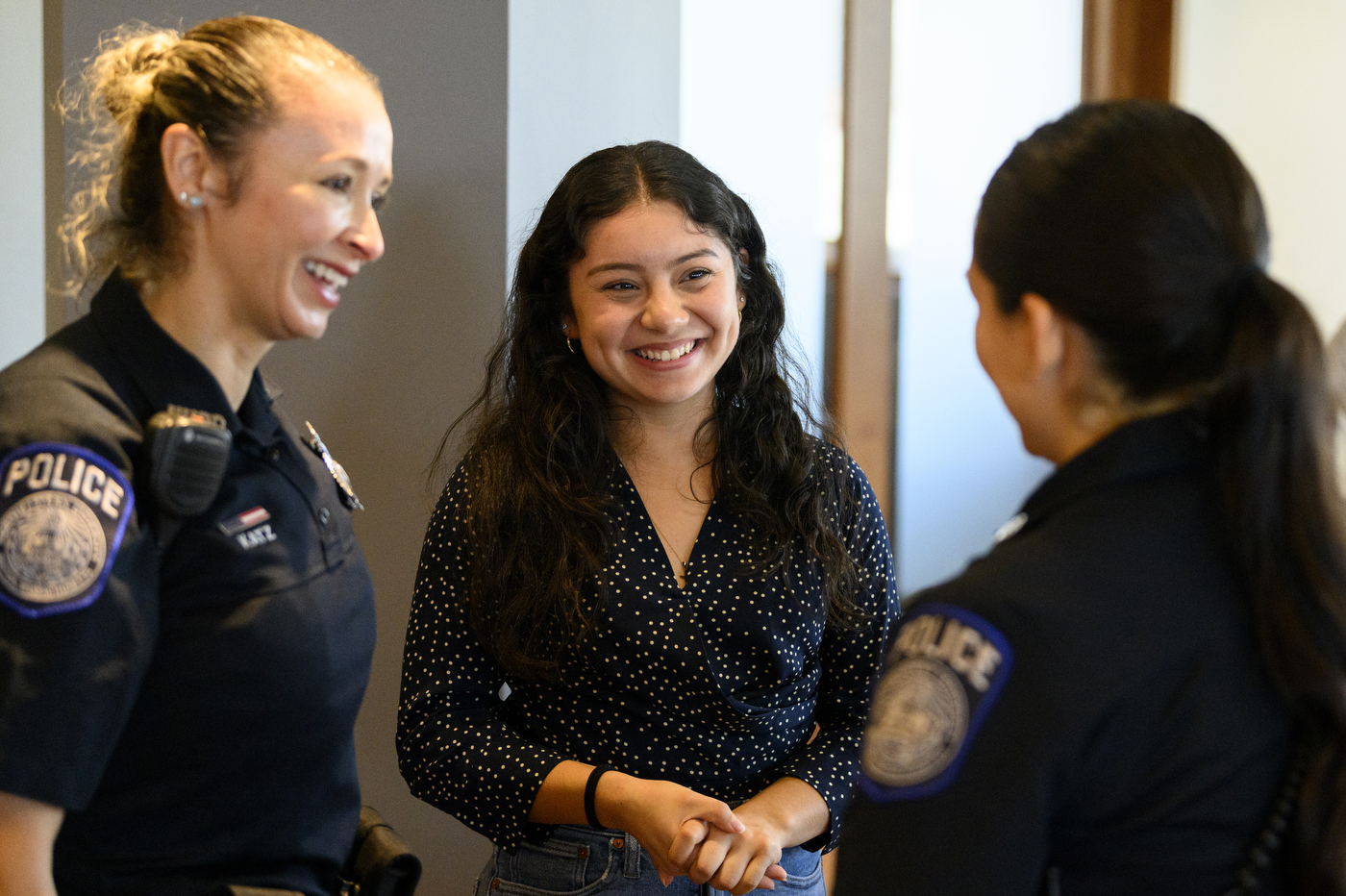 Three people are standing together in a circle, talking about a police mentorship program. 