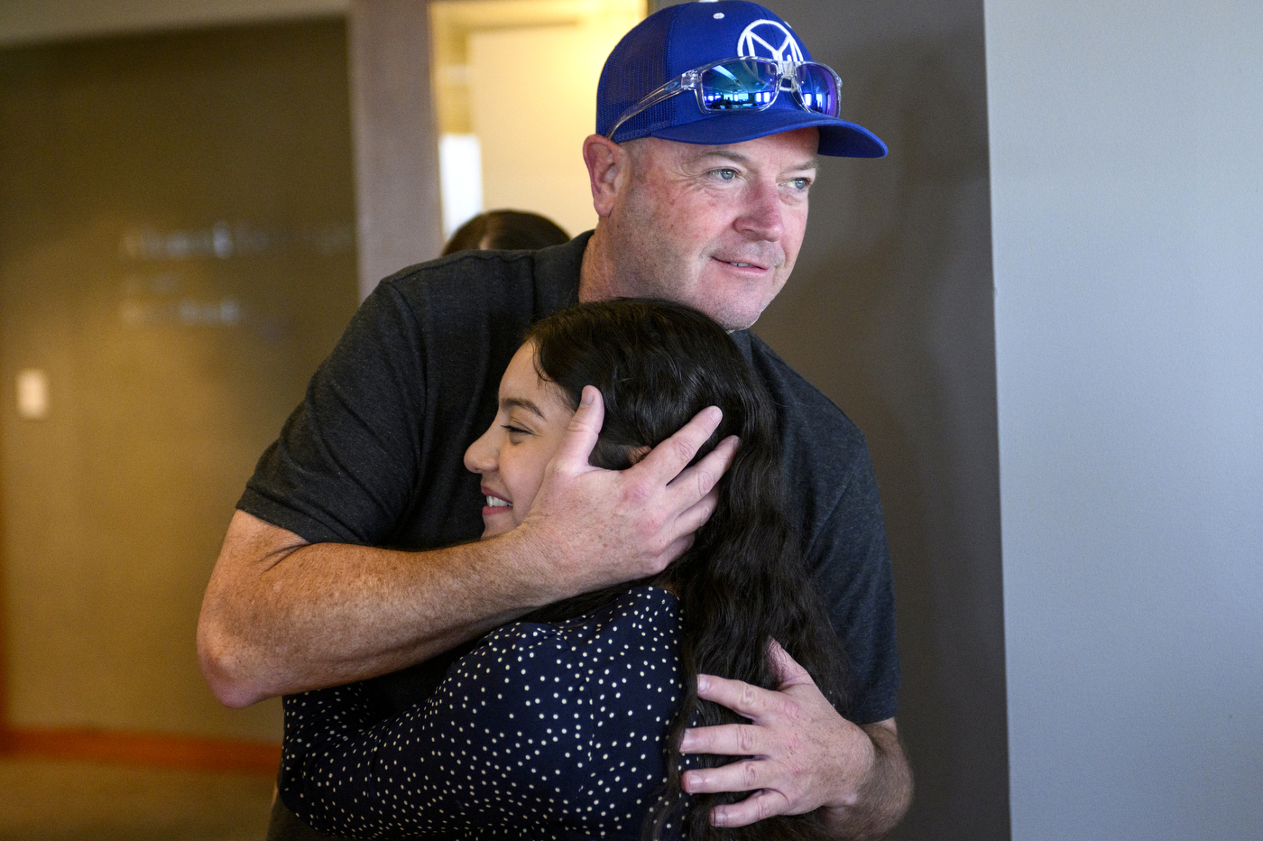 A person wearing a blue hat is hugging another person. 