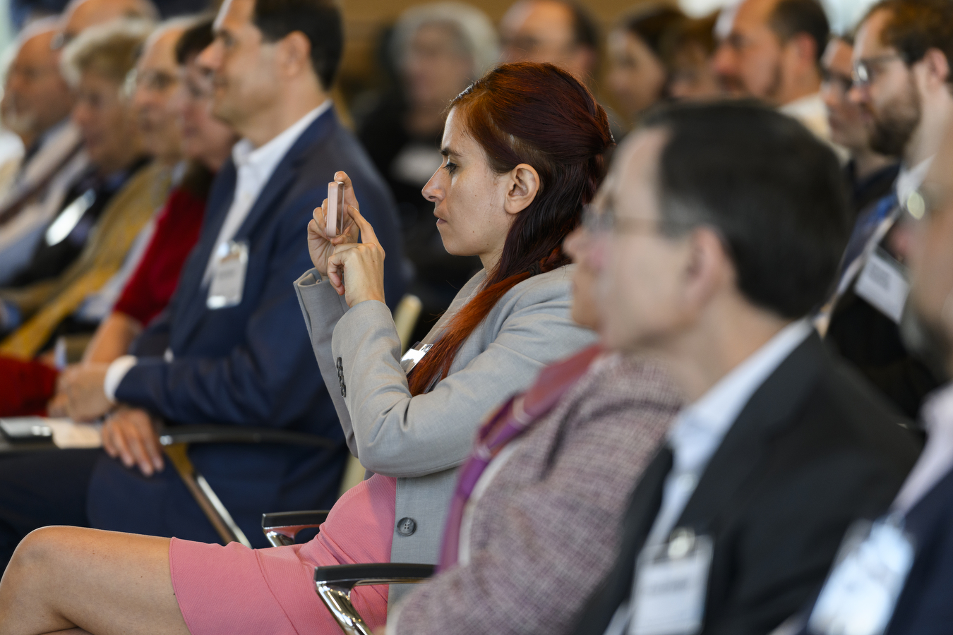 A person is holding a phone upwards while sitting next to several people. 