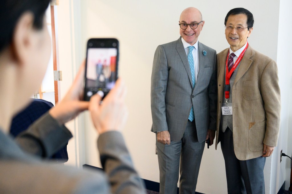 two men being photographed by a third person on their iphone