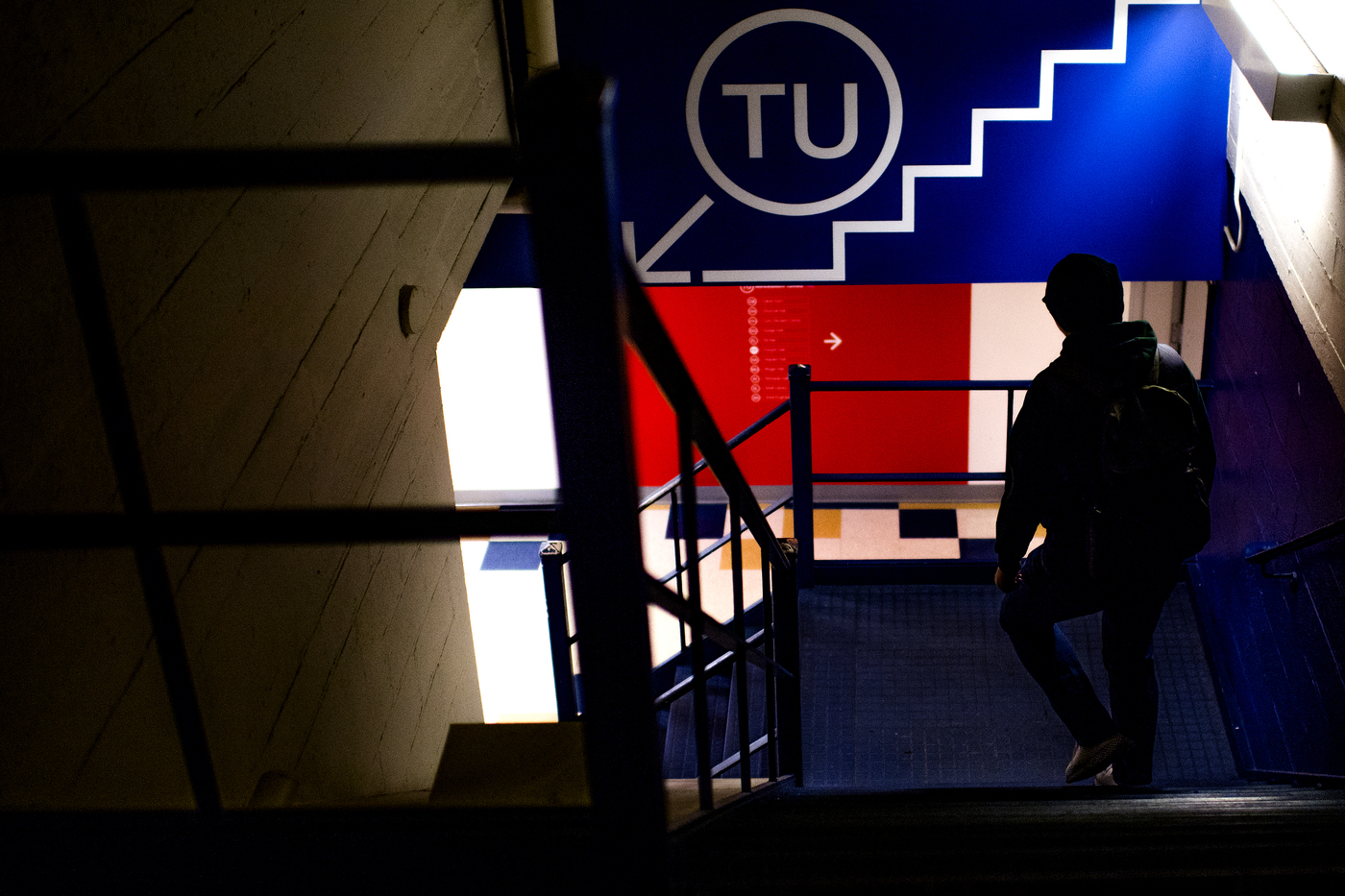 A person wearing a backpack is walking through a stairwell on Northeastern's Boston campus. 