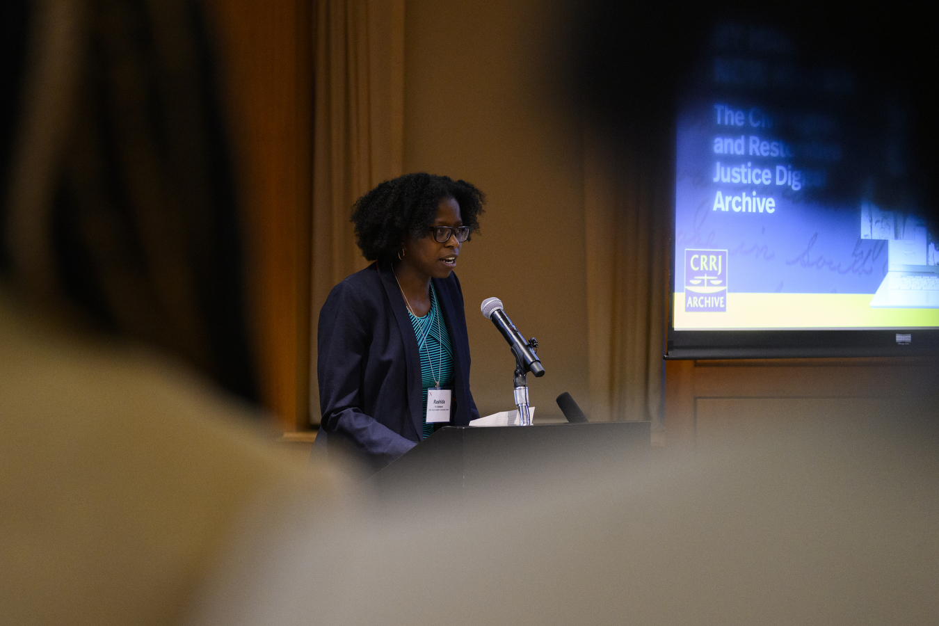 Rashida Richardson stands behind a podium and speaks into a microphone