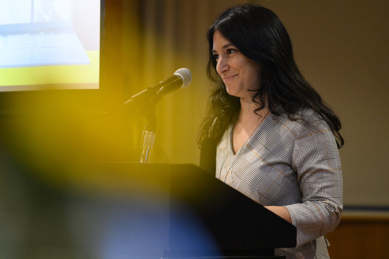 Kaylie Simon stands behind a podium and speaks into a microphone