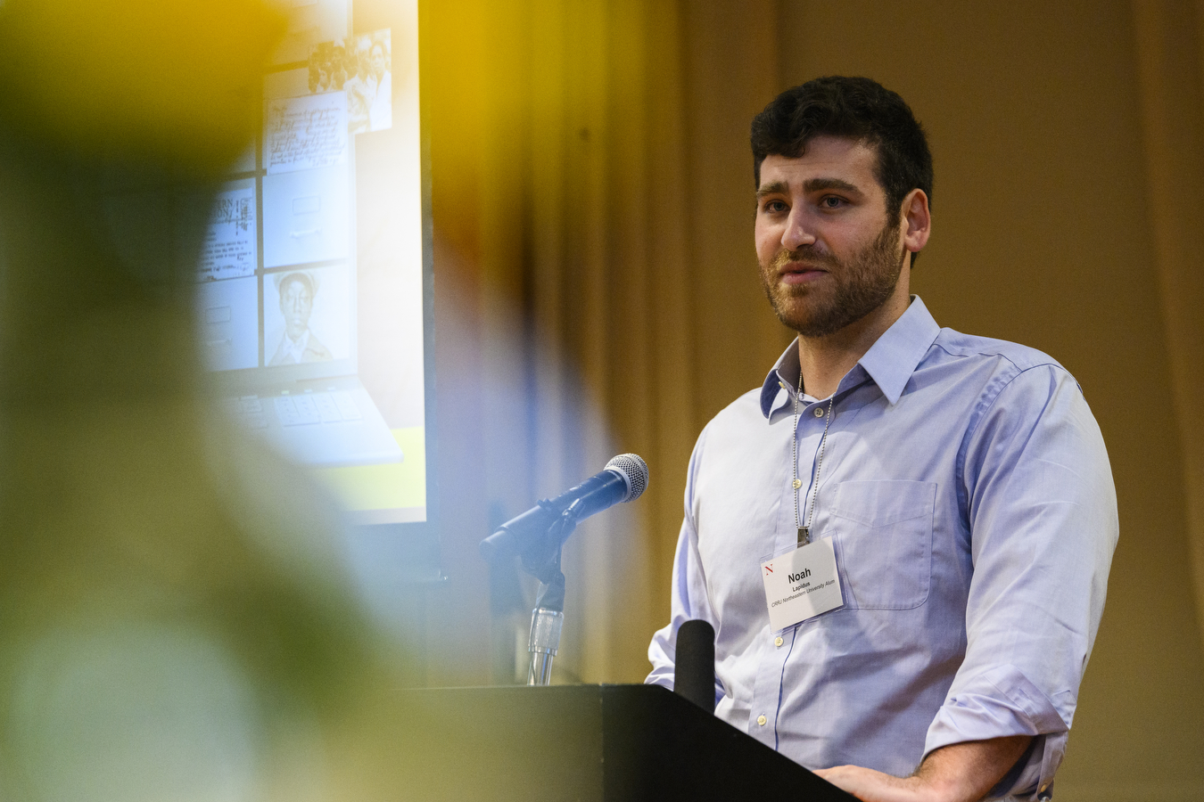 Noah Lapidus stands behind a podium and speaks into a microphone