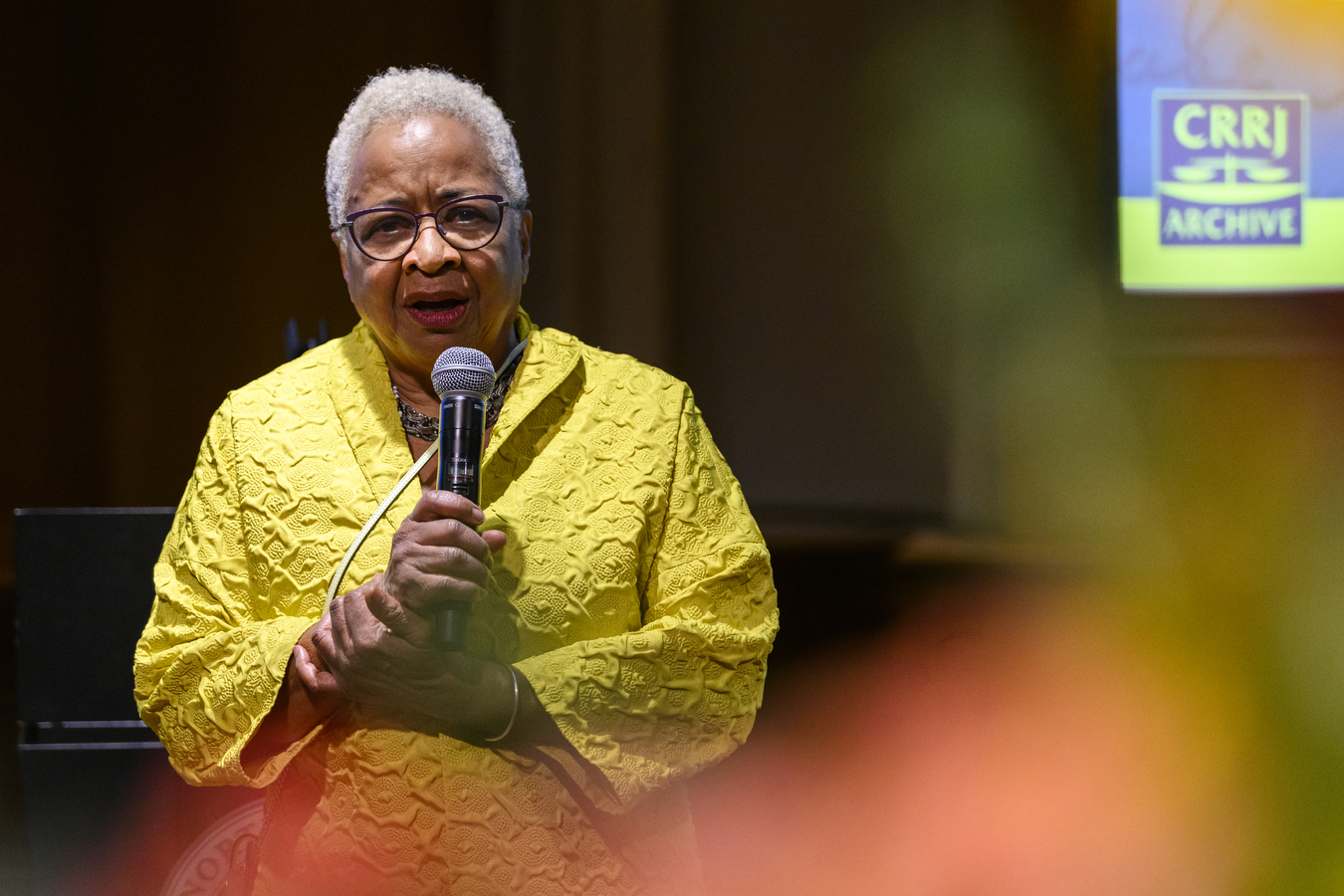 Margaret Burnham stands behind a podium speaking into a microphone