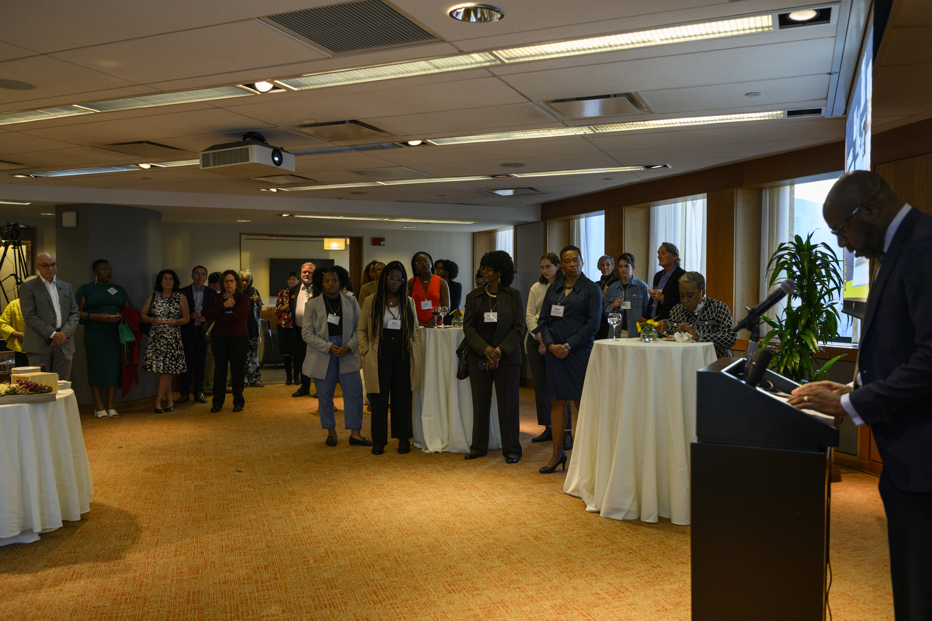 A person stands behind a podium presenting to a room full of people. 