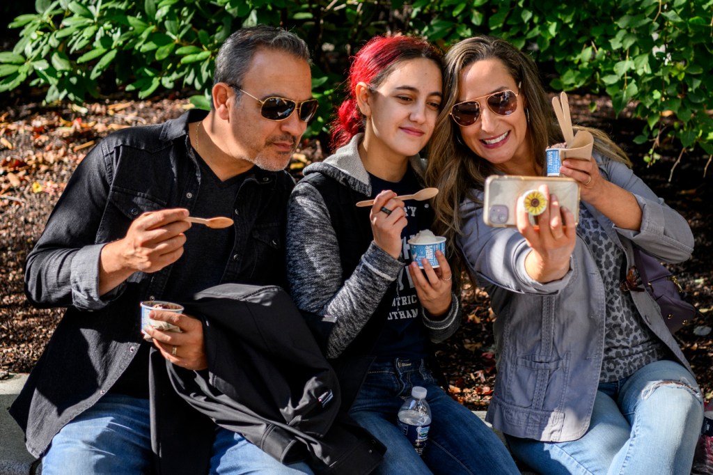 Three people are sitting together while eating ice cream during Northeastern's Friends & Family Weekend.
