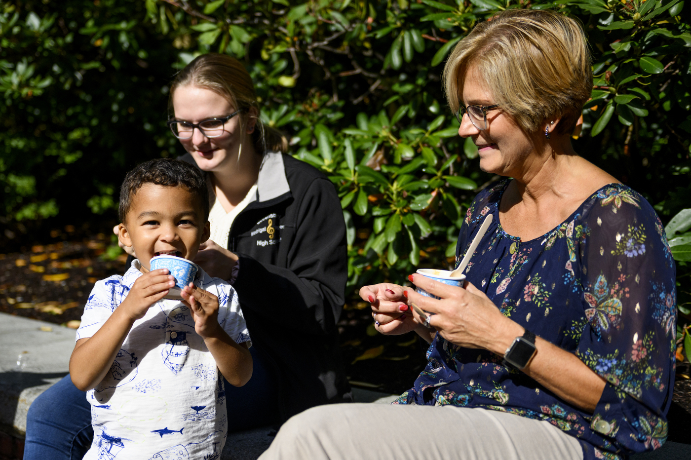 A child is eating ice cream while next to two other people eating ice cream.