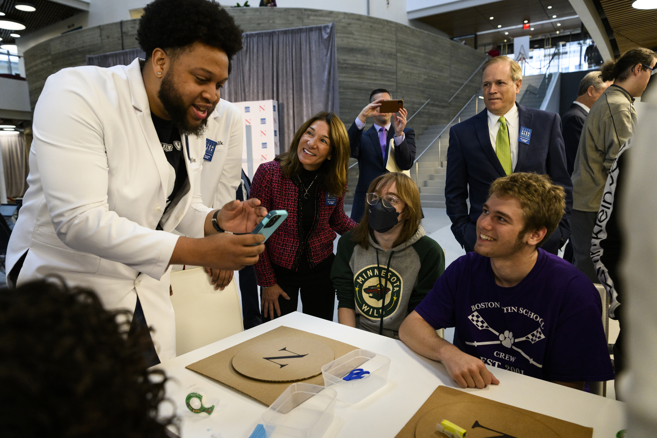 A person shows their phone to a crowd. 