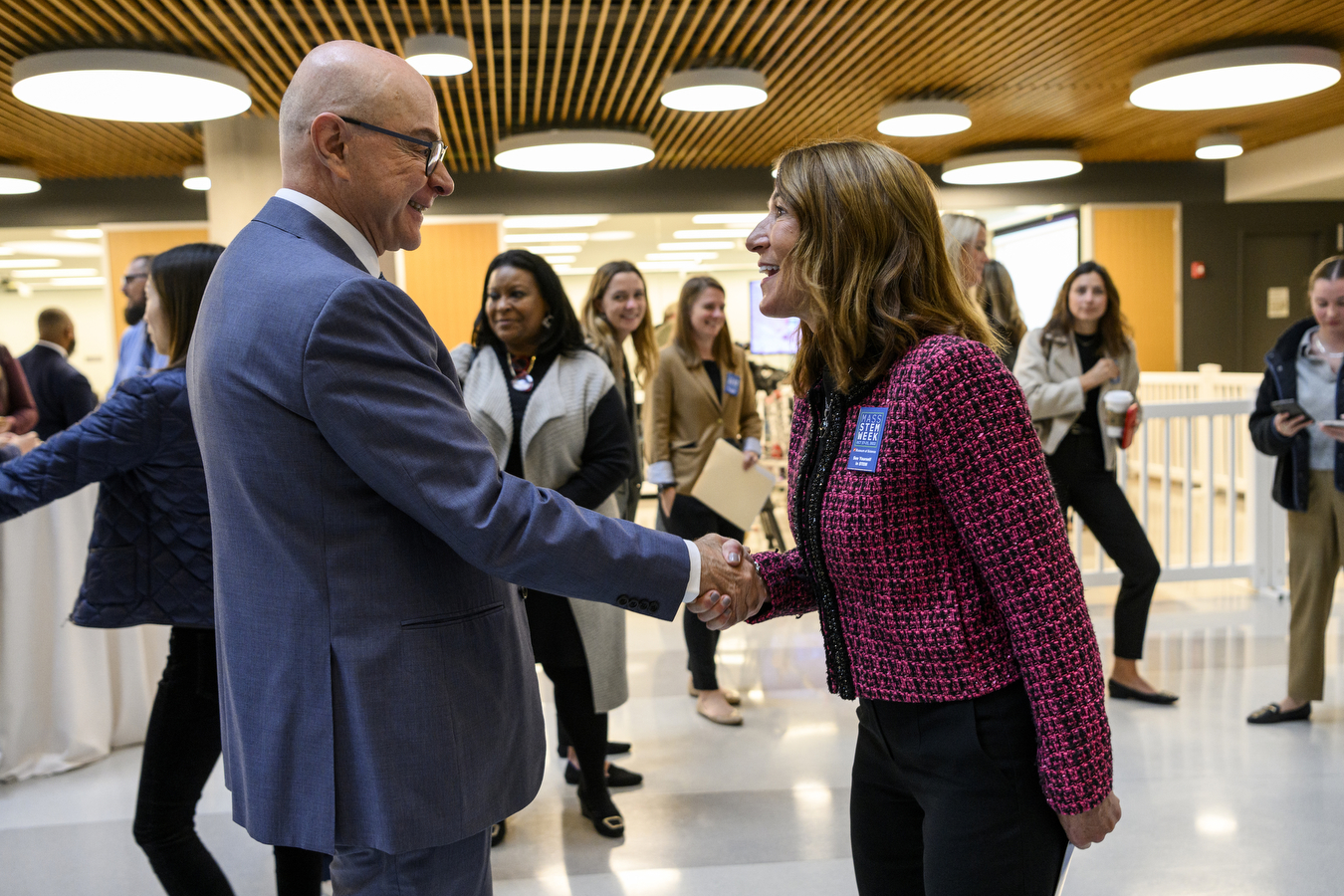 A person wearing a suit shakes hands with another person. 