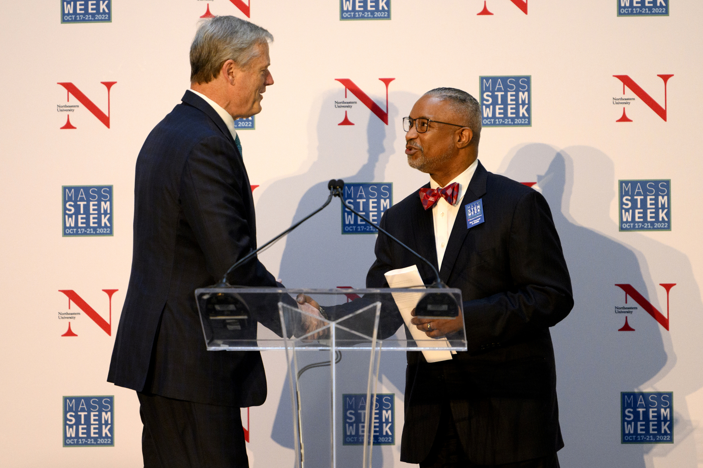 A person shakes hands with another person while they stand on a stage.