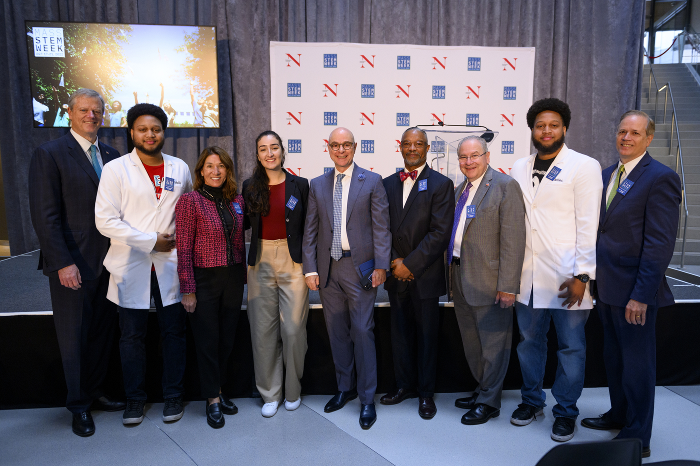 Nine people stand together in front of a stage to celebrate the start of STEM Week 2022. 