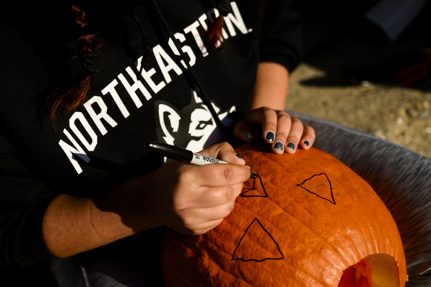 person drawing on a pumpkin with sharpie