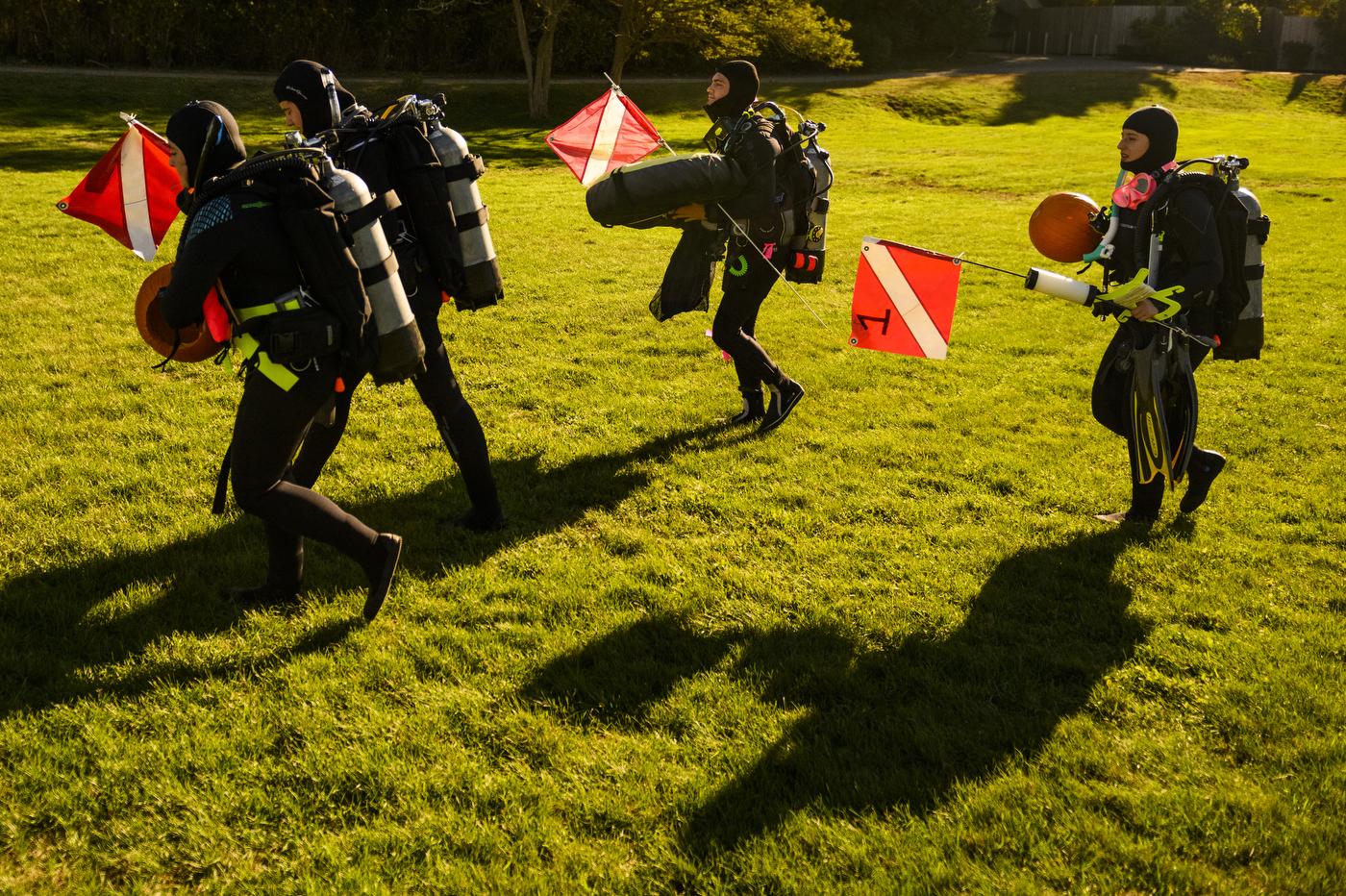 scuba divers carrying gear and red flags