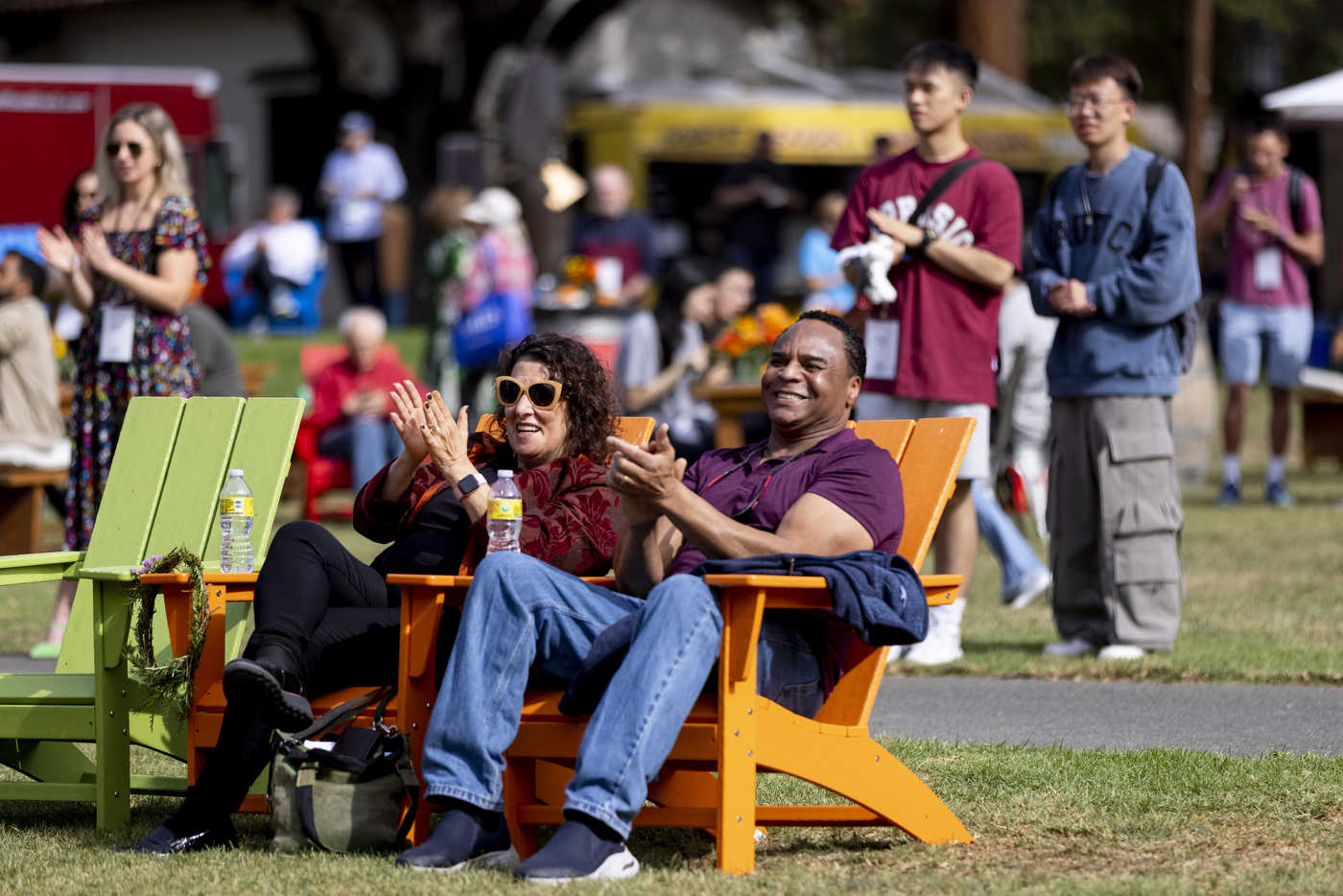 two people sit on chairs and clap