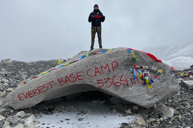 student standing on everest base camp rock