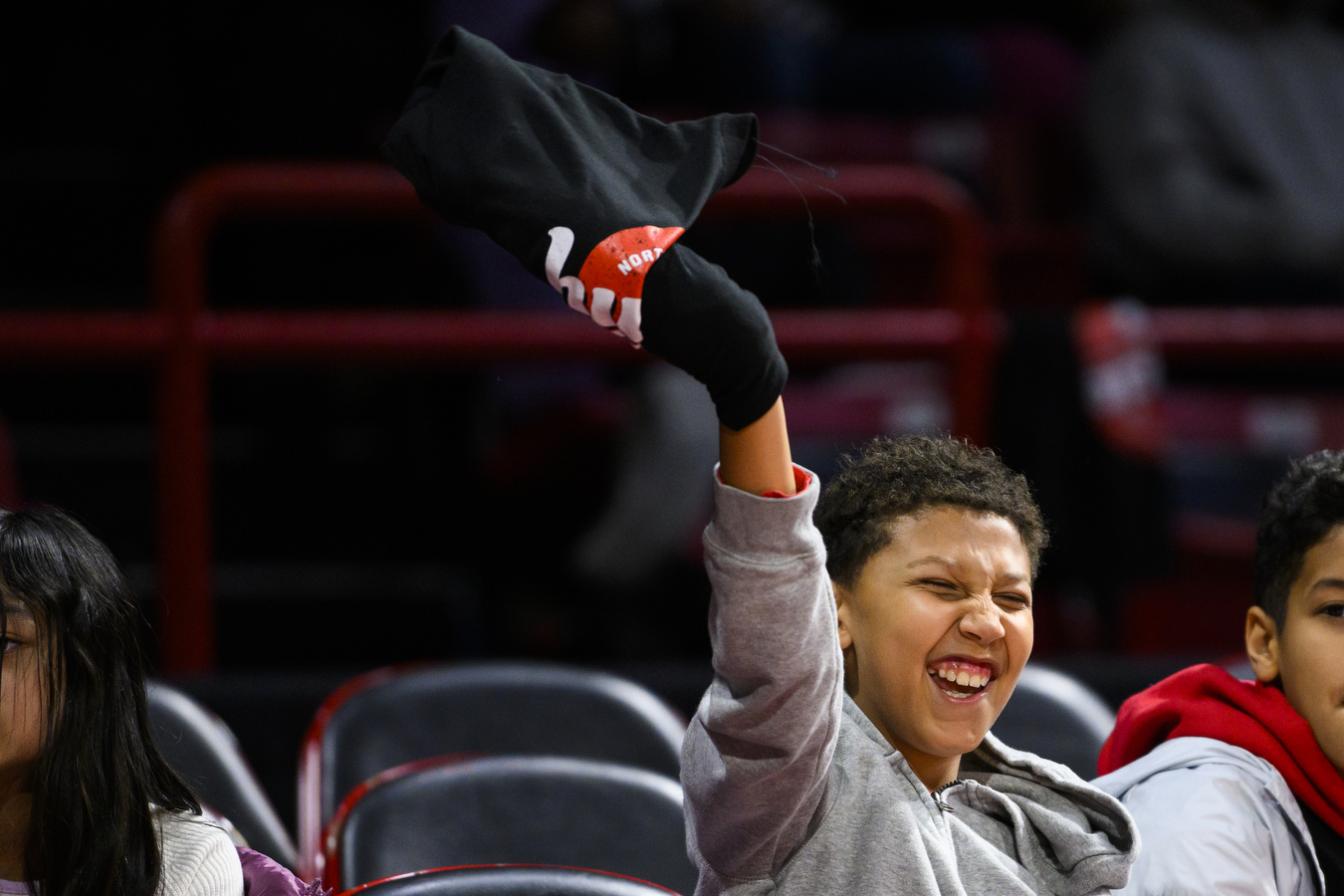 student waves -shirt in the air at basketball game