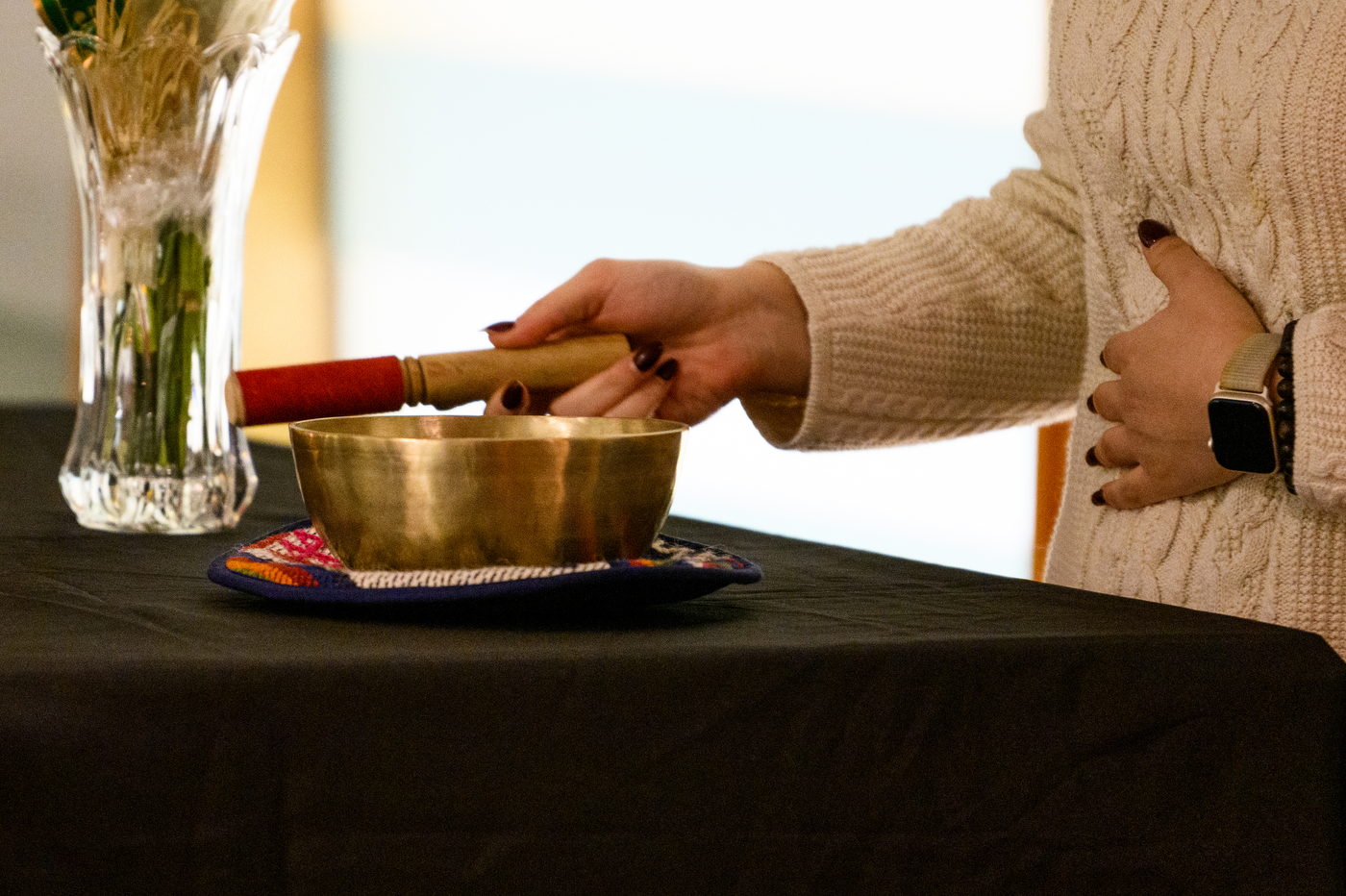 Person holding stick over gold bowl at bus crash vigil