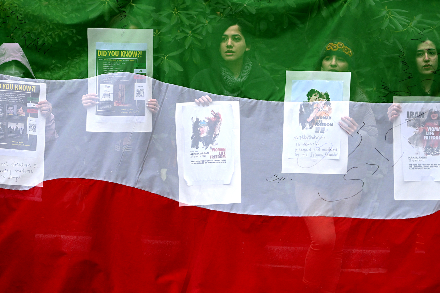 Students protesting with signs, overlaid by an Iranian flag