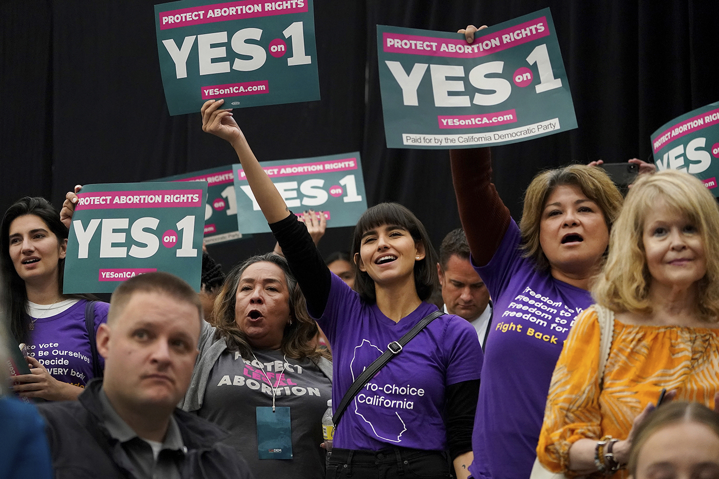 A group of people holding signs urging to vote to pass legislation to protect abortion in California