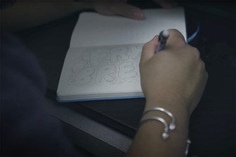 Close up of a person's hand as they draw in a notebook