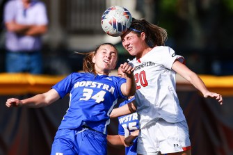 Two opposing soccer players compete to head the ball in mid-air