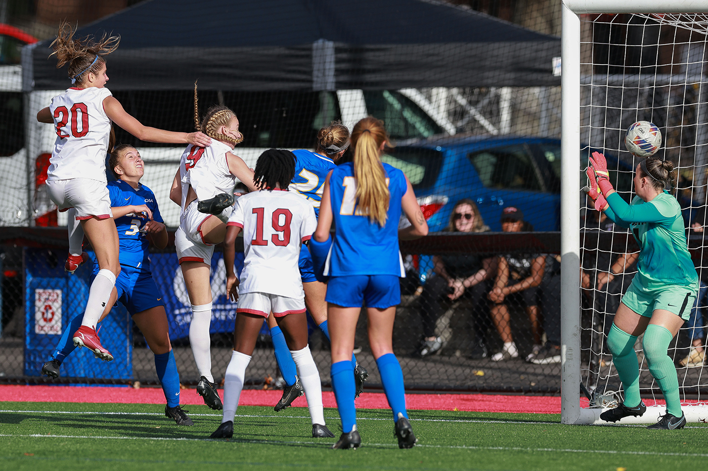 Multiple soccer players are fighting for control of a soccer ball. 