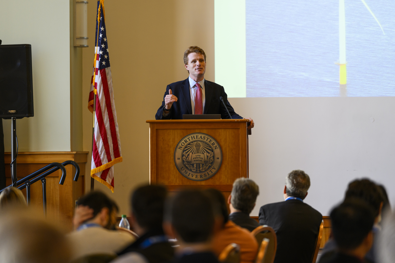 Former U.S. Rep. Joseph P. Kennedy III standing at a podium in front of a large crowd.