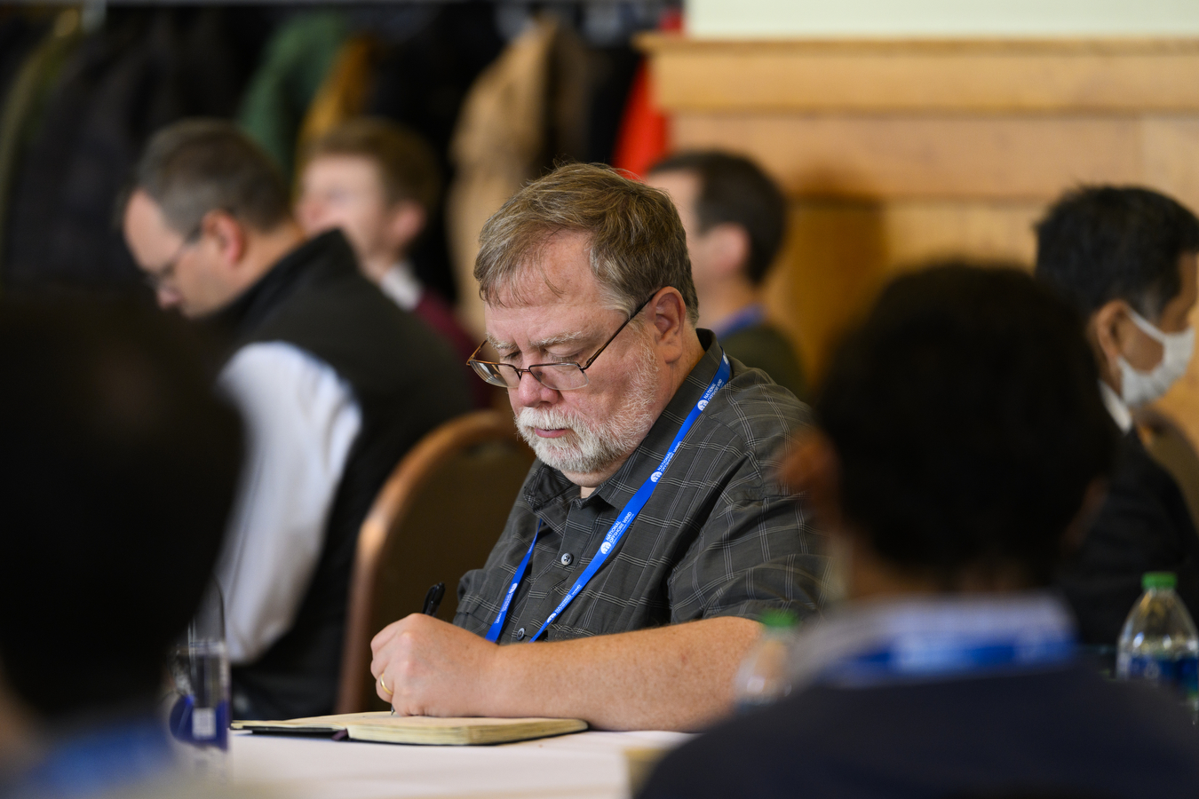 A person is writing in a notebook while sitting around a group of people. 