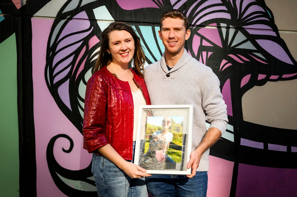 katie and chris hemphill posing with a portrait of samantha hemphill