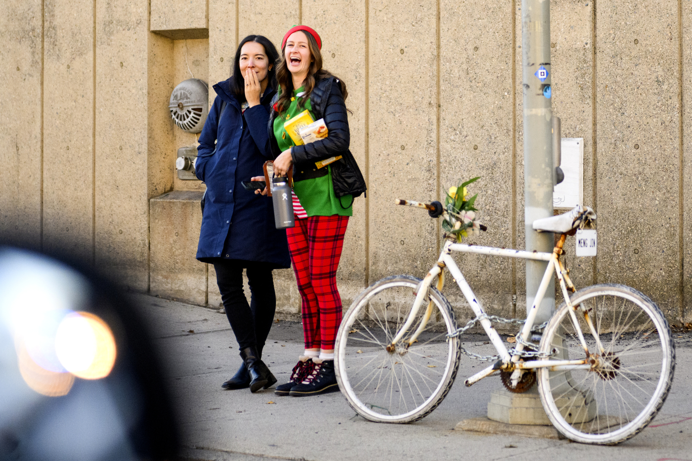 two people standing next to a parked bike laughing