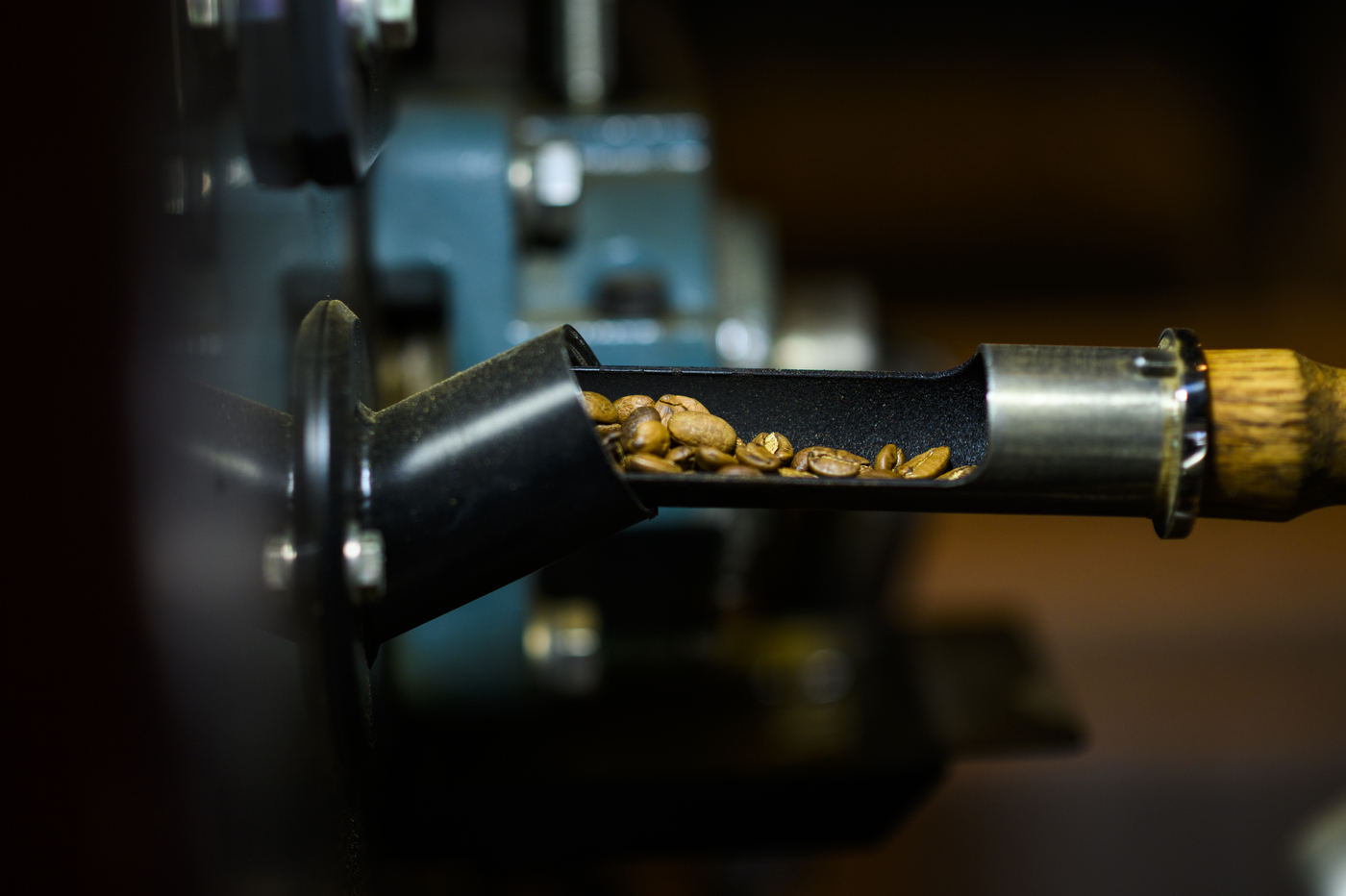 A black machine filters coffee beans through a tube. 