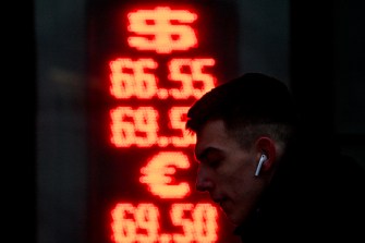 man wearing airpods silhouetted against black screen with red currencies on it