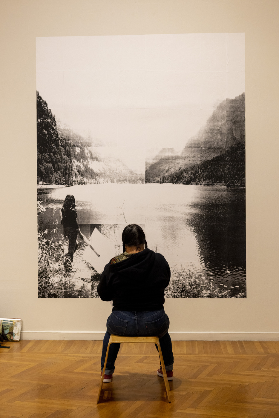 person sitting on stool in front of painting at mills college art museum