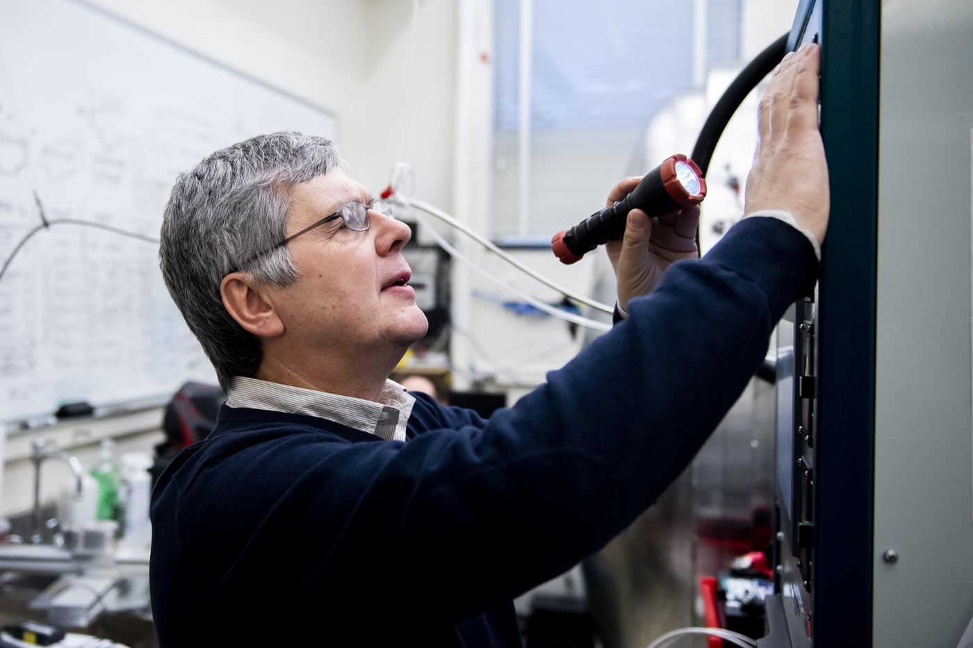 Oleg Batishchev points a flashlight at a machine. 