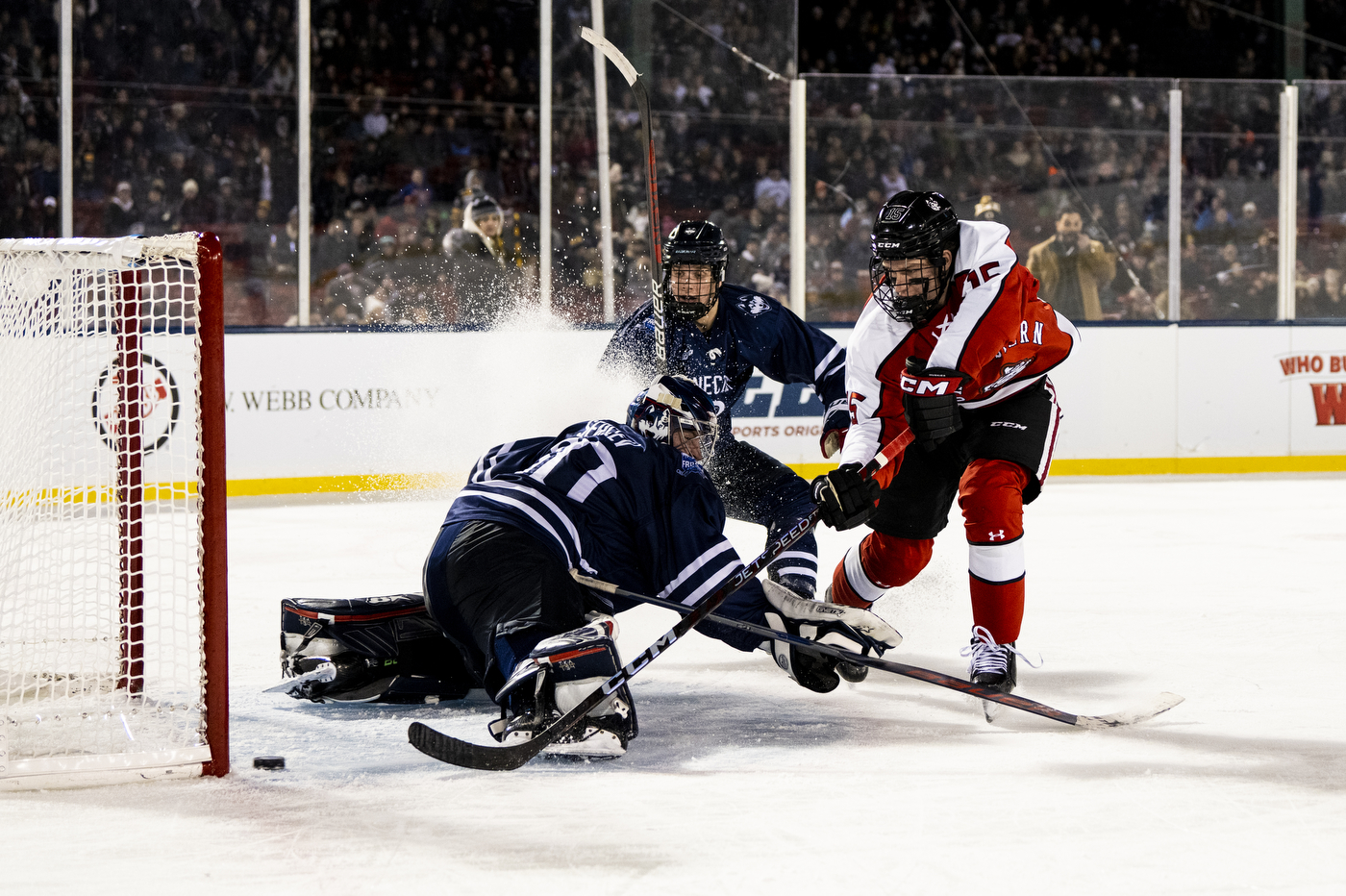 Three hockey players playing on an ice skating rink.